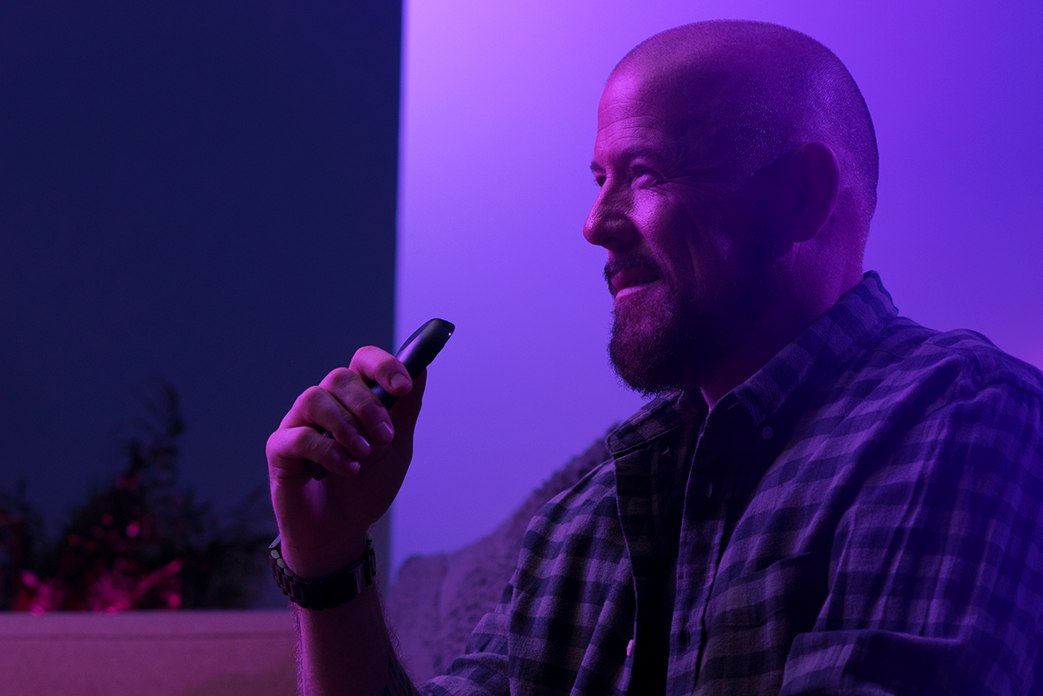 Image of a man holding up a remote to speak to