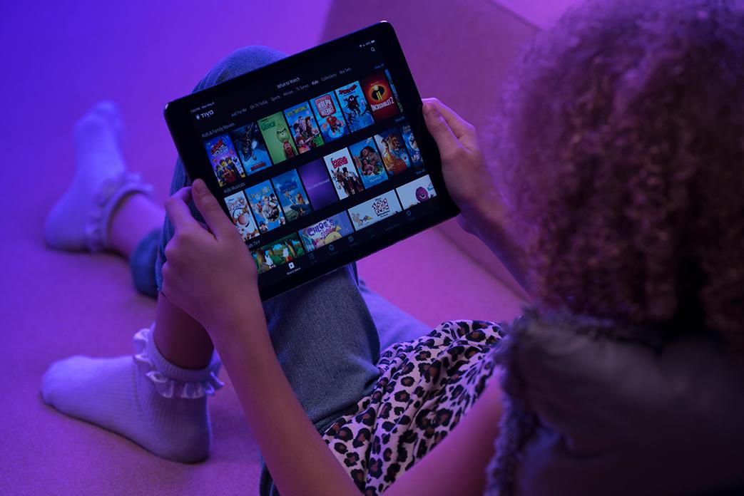 Image of an ipad being held by a girl showing TiVo app