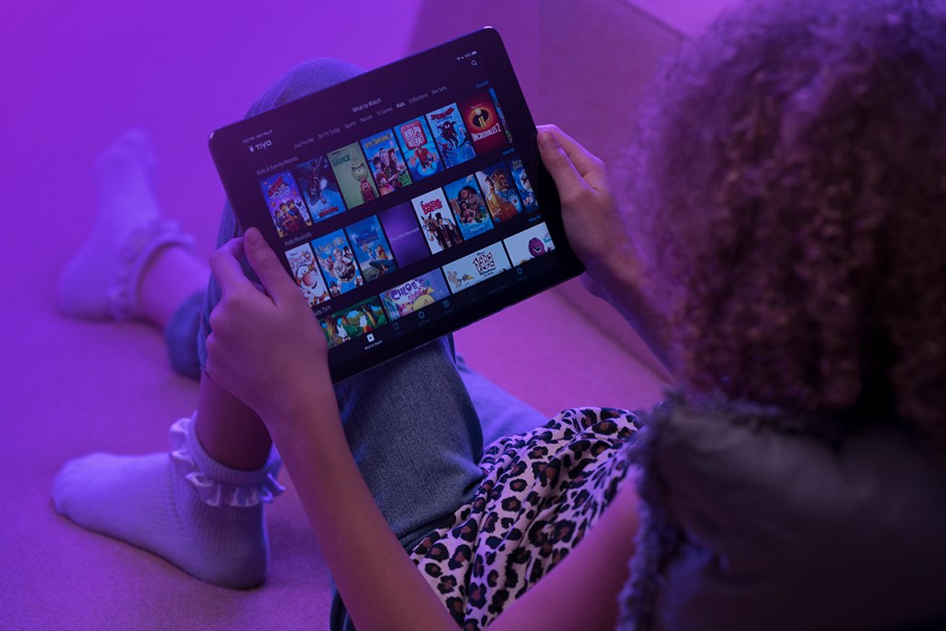 Image of an ipad held by a girl showing TiVo app